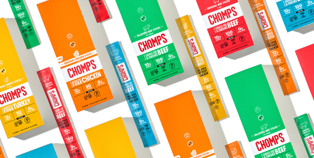 A collage of colorful Chomp's boxes and sticks arranged diagonally on a white background, showing flavors including beef, chicken, and turkey.