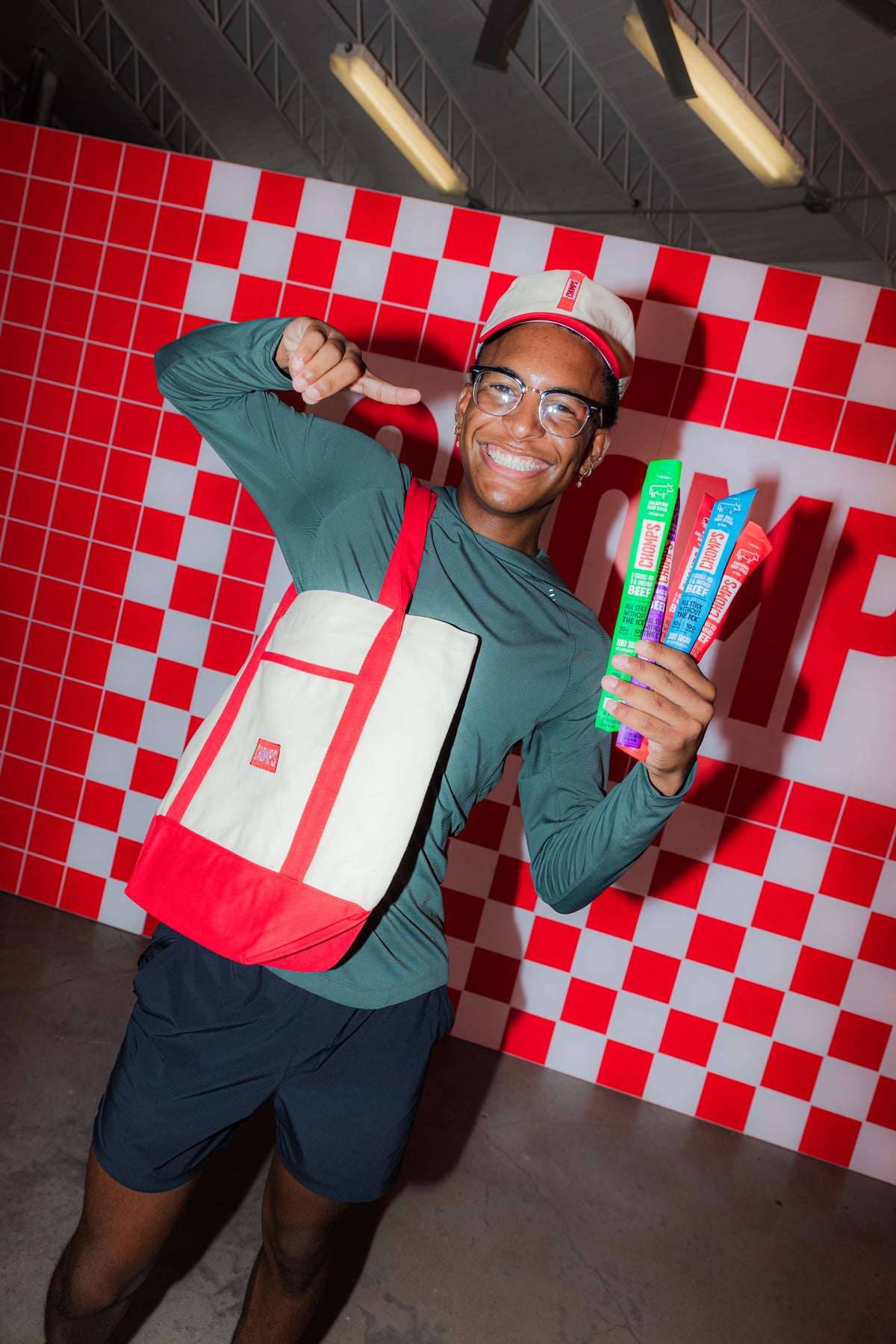 A man posing for a photo with a handful of Chomps and a Chomps tote bag.