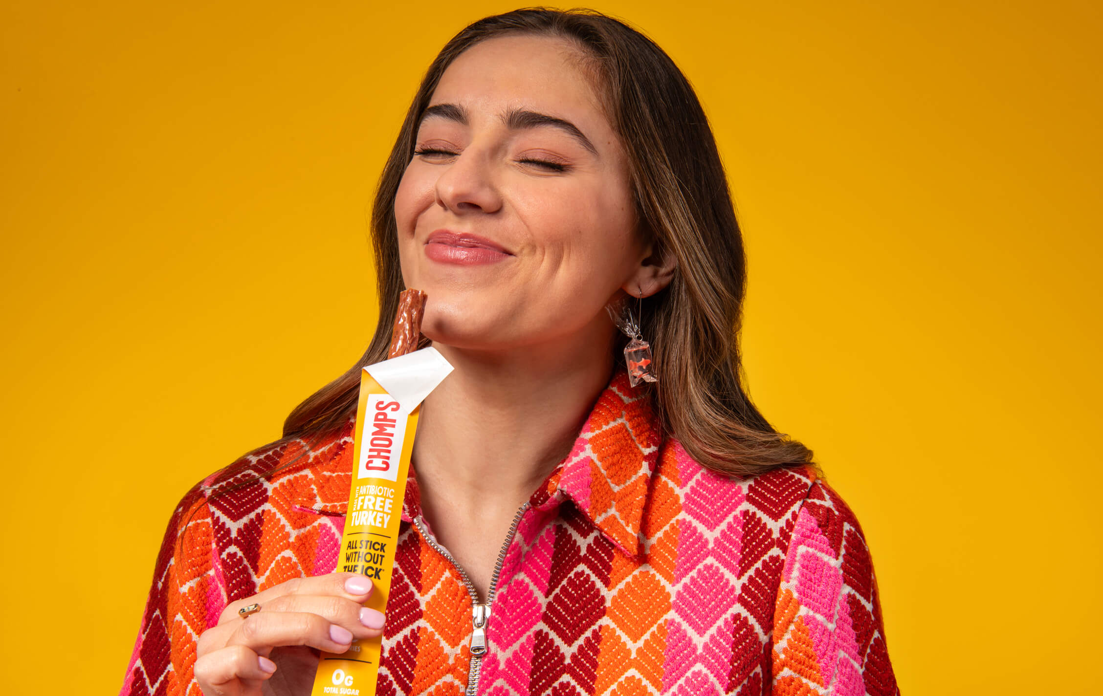 Woman holding a Chomps stick against a yellow background