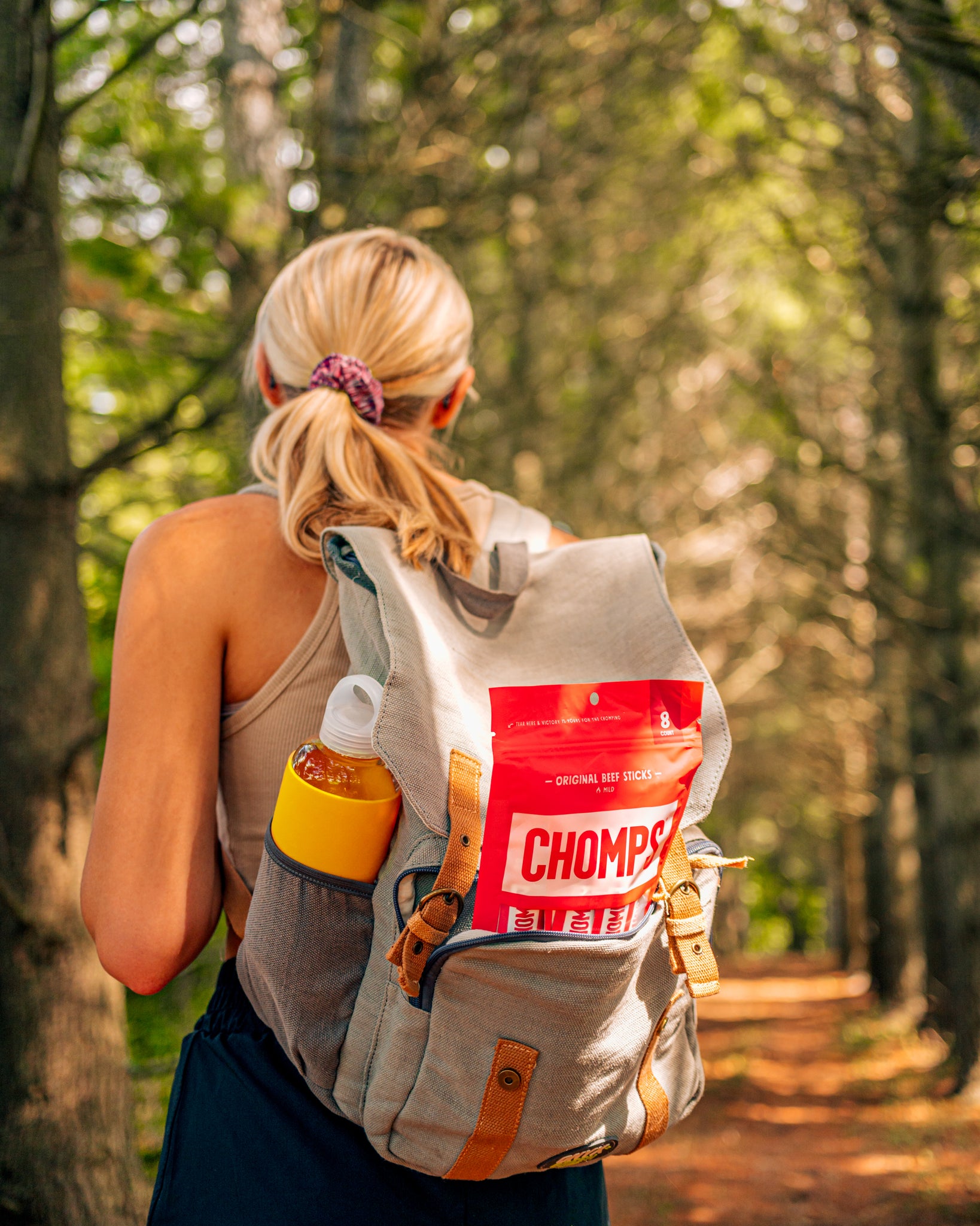 A woman hiking with Chomps in her backpack.