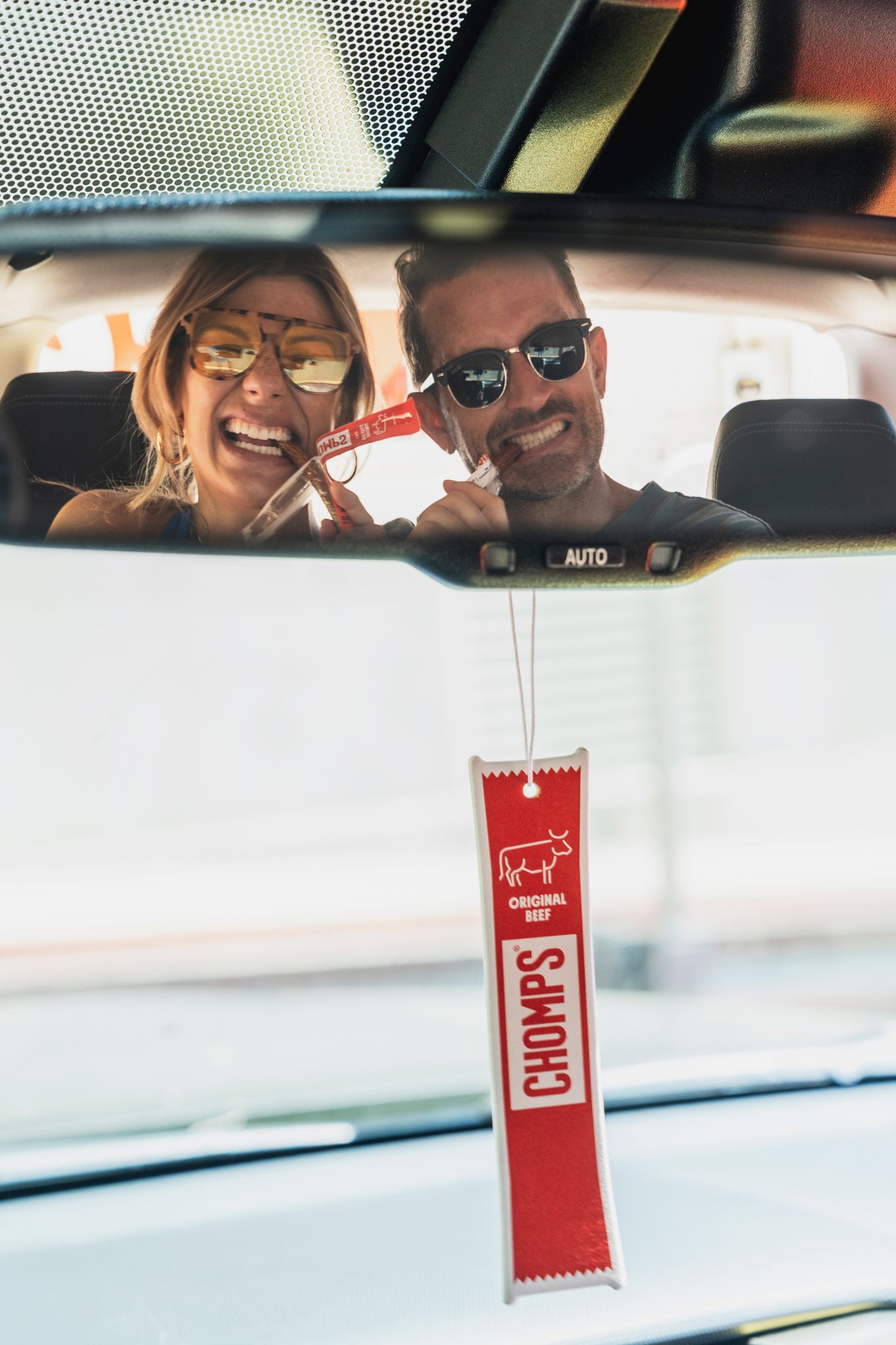 A couple sitting in the car energetically eating Chomps.