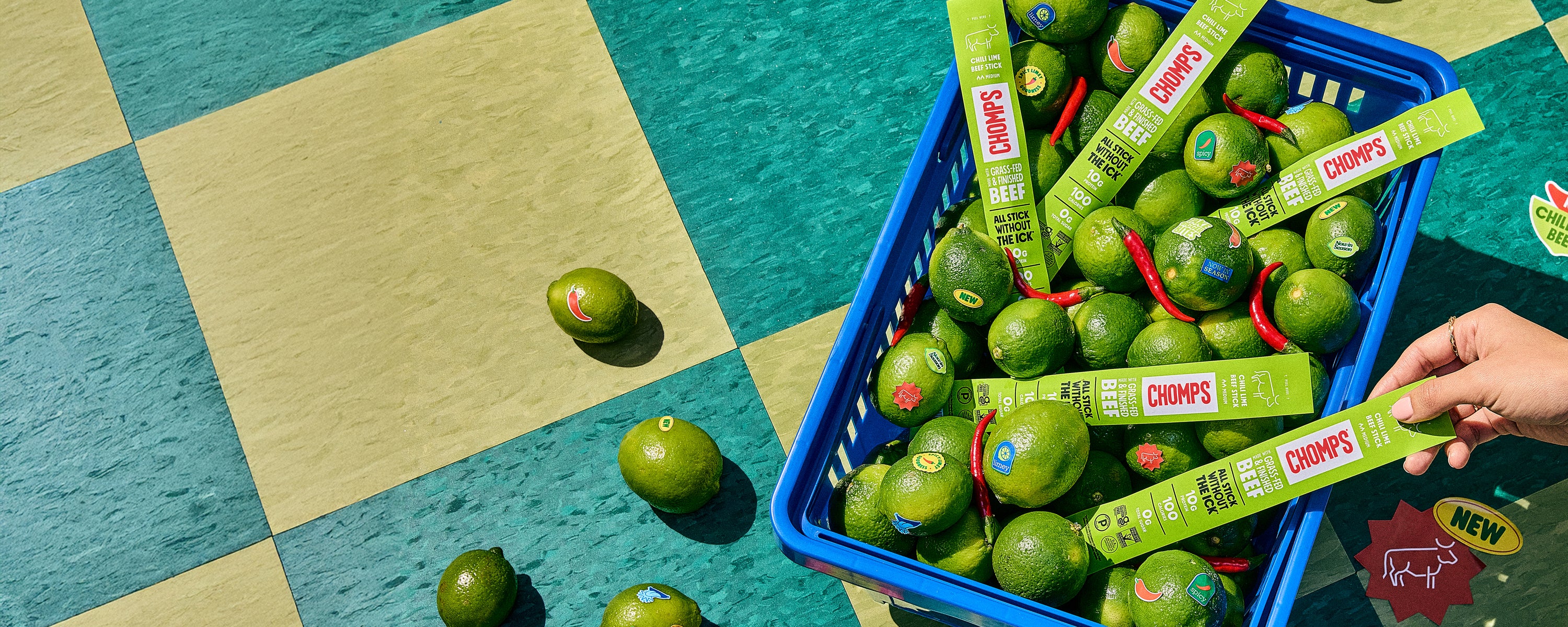 Limes with Chomp Meat Sticks in a blue basket on a checkered floor.